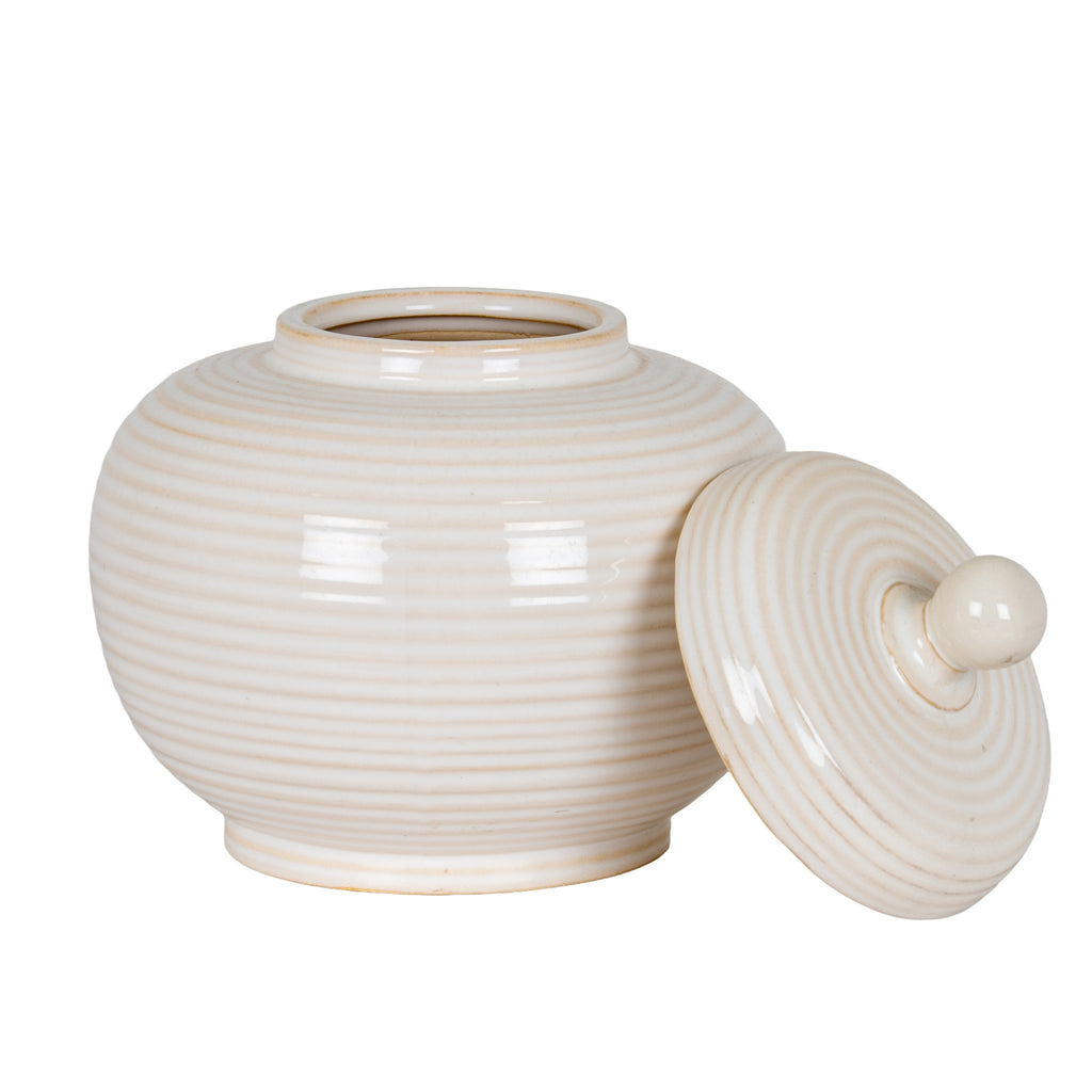 Rounded ribbed jar with its mouth exposed and the circular lid leaning against its right side, showing concentric rings around the knob.