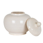 Rounded ribbed jar with its mouth exposed and the circular lid leaning against its right side, showing concentric rings around the knob.