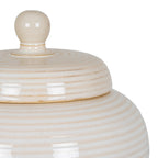 Close-up of the jar's rounded lid knob and glossy cream-white rings, with fine speckling and warm beige shading in the grooves.