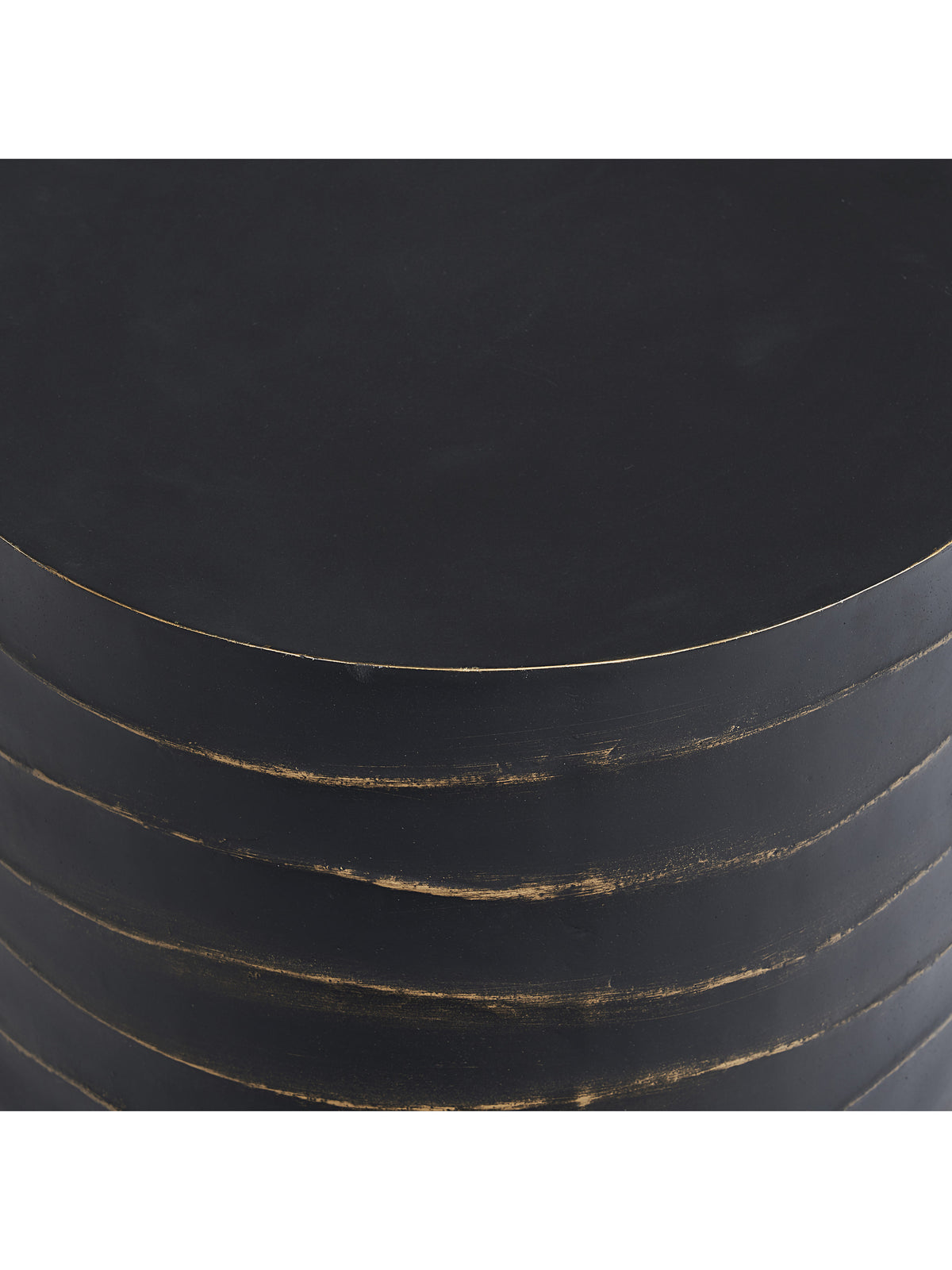 Close-up of the black circular tabletop and textured rippled sides with uneven brass-coloured painted accents.