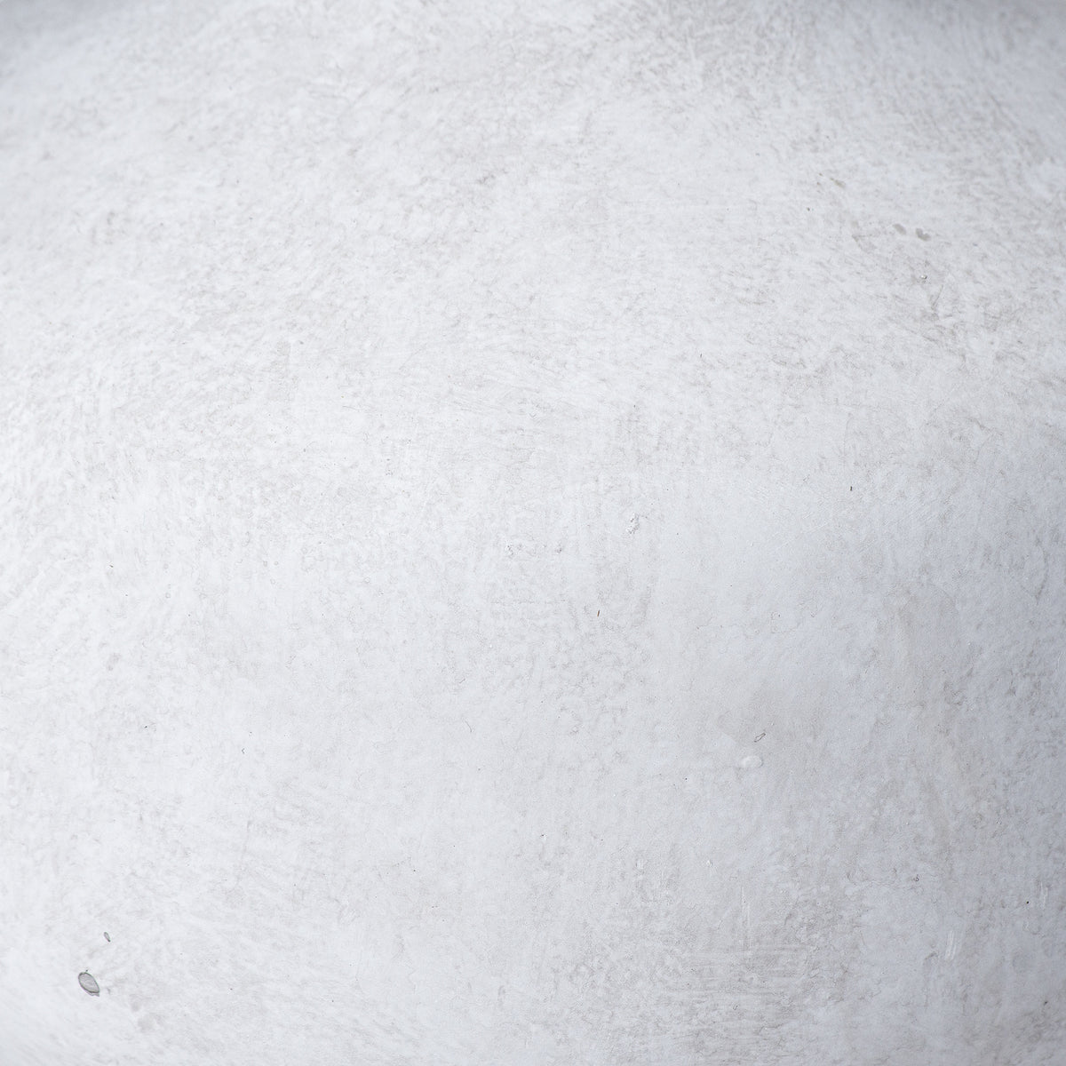 Close-up of the vase surface showing off-white and light grey mottling, fine rubbed marks and scattered darker flecks.