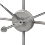Close-up of the clock’s circular central hub and overlapping hands, showing the rubbed, brushed-looking silver-toned surface.