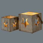 Two differently sized star candle holders shown side by side, with warm light visible inside and through their star openings.