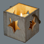 Square star candle holder pictured with a glowing candle-shaped light inside, warm illumination visible through the open top and star cut-outs.