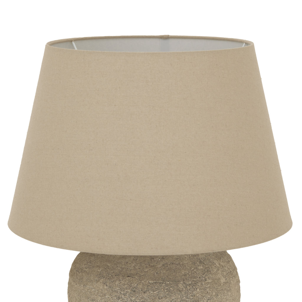 Close-up of the broad tapered beige lampshade, showing its fine woven appearance, open upper rim and part of the textured base below.