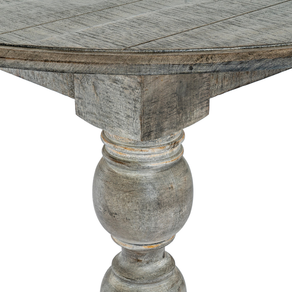 Close-up of the dining table's curved profiled edge and the upper section of a leg beneath it.