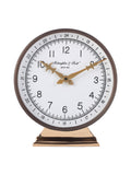 Front view of a round mantel clock with an ivory dial, black numerals, ornate gold-toned hands and a stepped gold-toned pedestal.