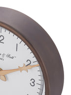 Close-up of the clock's bronze-toned rim beside black minute marks and a decorative gold-toned hand.