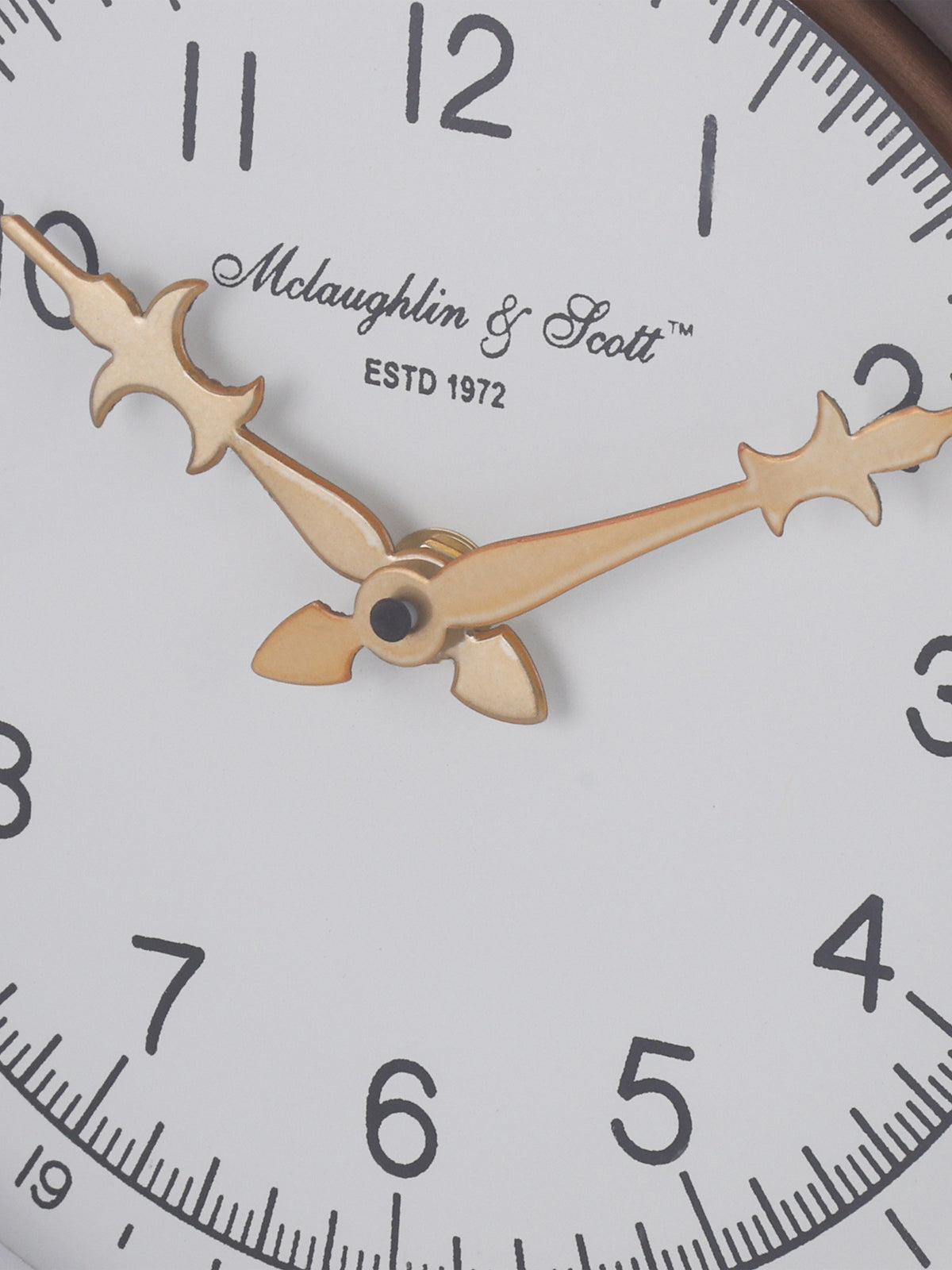 Close-up of the ornate gold-toned clock hands over the ivory dial with black numerals and printed lettering.