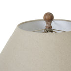 Close-up of the rounded brown finial above the pale woven-looking shade, with its open top visible.