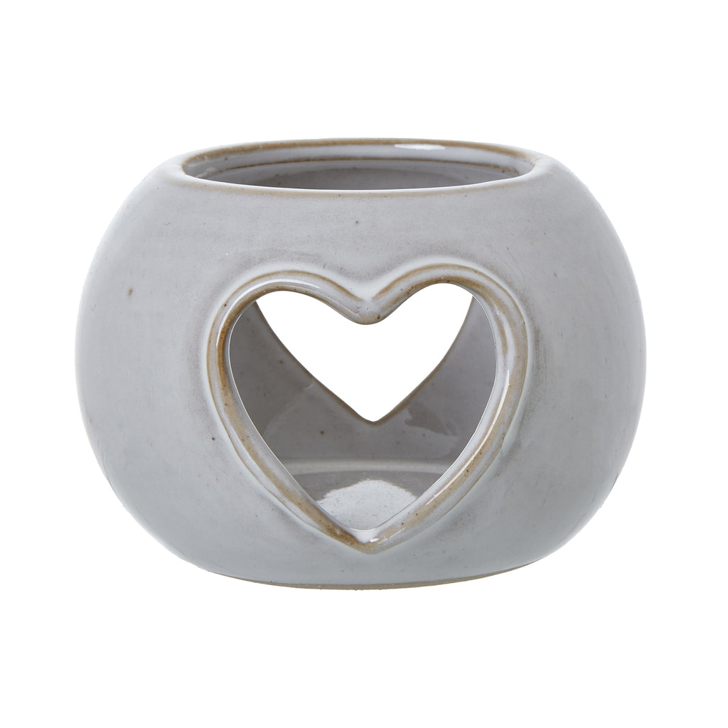 Front view of the rounded off-white candle holder, showing a tan-edged heart opening and a second heart visible through it.