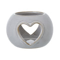 Front view of the rounded off-white candle holder, showing a tan-edged heart opening and a second heart visible through it.