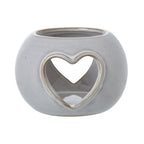 Front view of the rounded off-white candle holder, showing a tan-edged heart opening and a second heart visible through it.