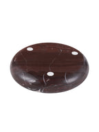 Underside of the red marble bowl with natural pale veins and three circular white pads.