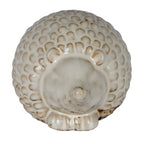Front view of the rounded hedgehog decoration, showing its central nose, small ears and cream scales edged with brown shading.