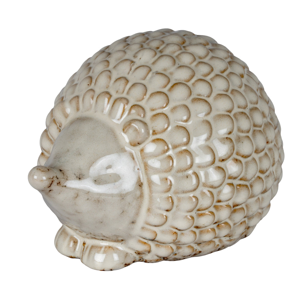 Three-quarter view of a cream-white hedgehog decoration with a domed scale-patterned back, pointed snout and short front feet.