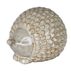 Three-quarter view of a cream-white hedgehog decoration with a domed scale-patterned back, pointed snout and short front feet.