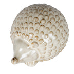 Hedgehog decoration viewed from above at an angle, showing the domed cream-white back with brown-shaded scales and the nose pointing towards the lower left.