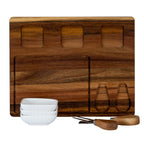 Front view of the board showing three empty rounded-square bowl wells and two shaped utensil recesses, with white bowls stacked and utensils arranged in front.