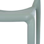Close-up of the green-grey chair's seat edge and leg junction, showing the fine pebbled surface texture.