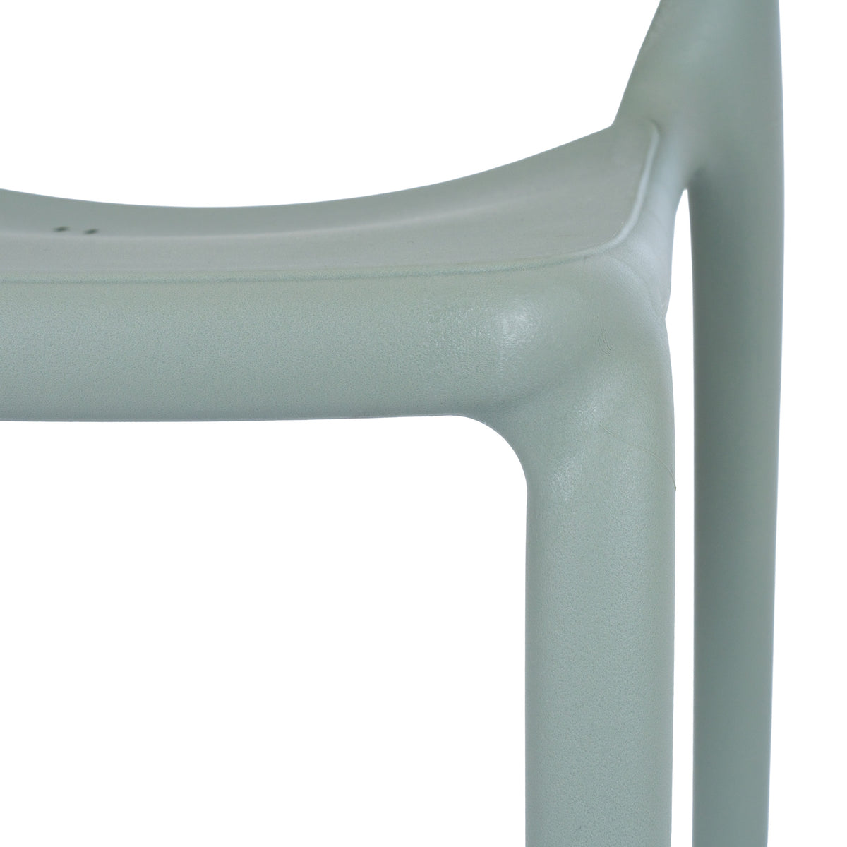 Close-up of the green-grey chair's seat edge and leg junction, showing the fine pebbled surface texture.