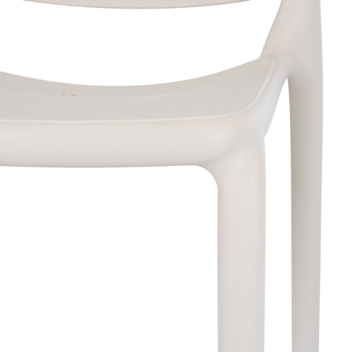 Close-up of the putty chair's seat edge and legs, showing the fine pebbled texture and curved outline beside the back.