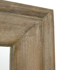 Close-up of the mirror's upper frame corner, showing the sloping moulding and pale grain-like streaks across the brown finish.