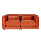 Front view of the rust-orange sofa with a central division, two thick seat cushions and short dark feet.