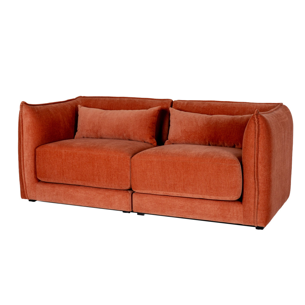 Angled view of the rust-orange sofa showing two seat sections, rectangular back cushions and rounded outer arms.