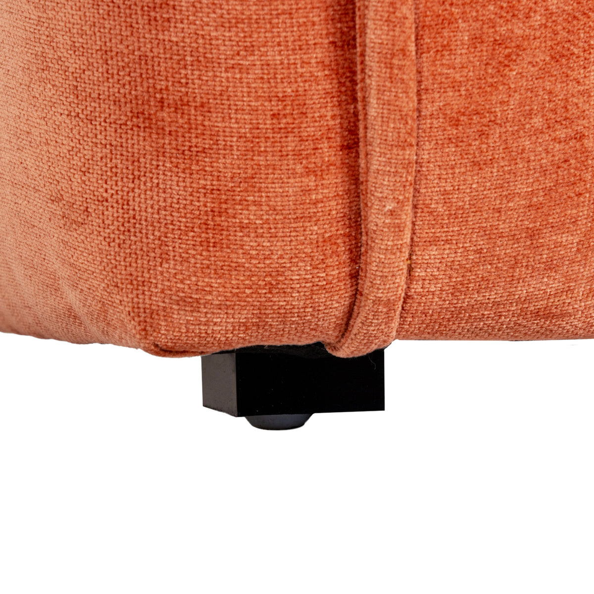 Close-up of a short dark rectangular foot with a small rounded pad beneath the rust-orange upholstered chair base.