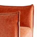 Close-up of the matching rust-orange rectangular cushion and the chair behind it, showing textured upholstery and raised edges.