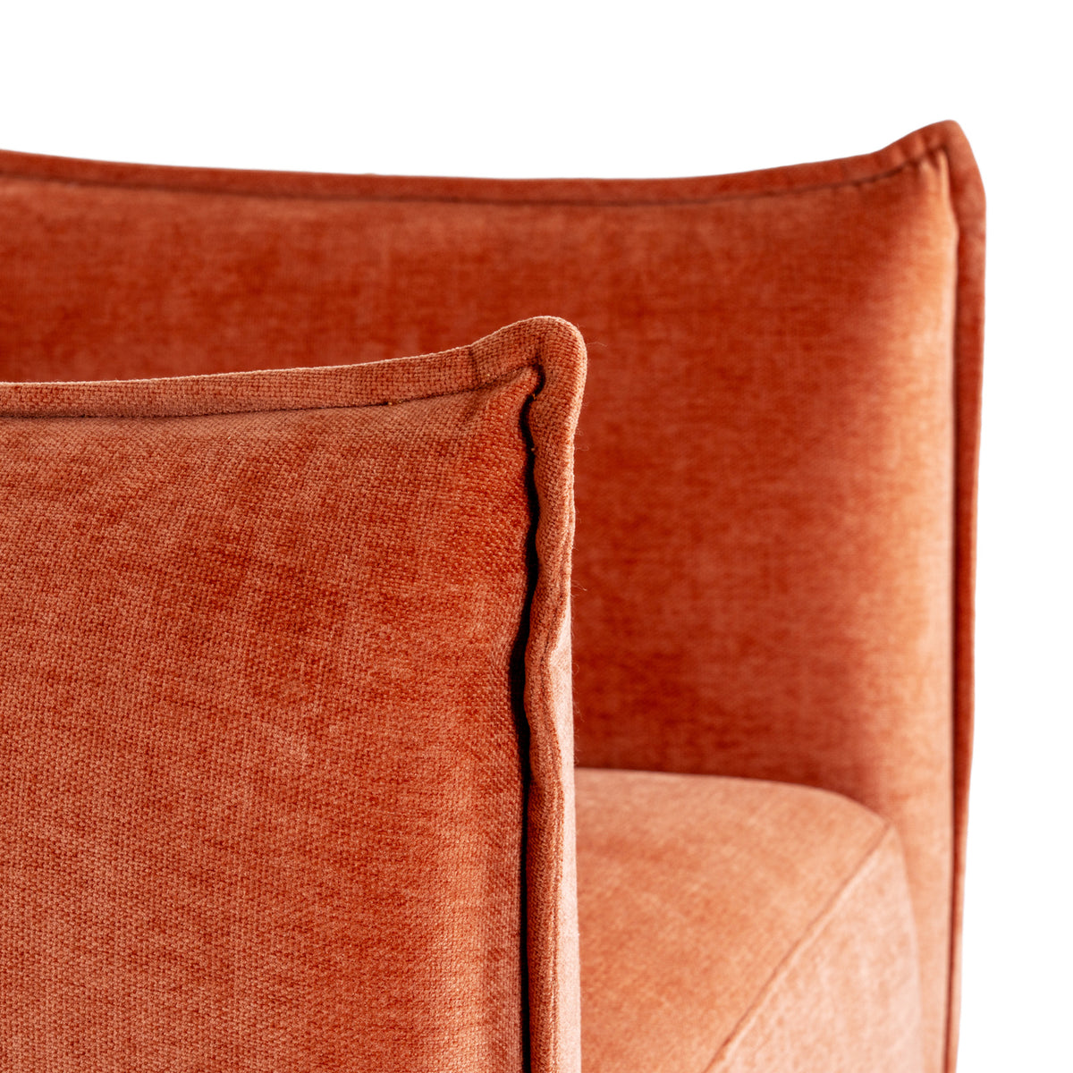 Close-up of the matching rust-orange rectangular cushion and the chair behind it, showing textured upholstery and raised edges.