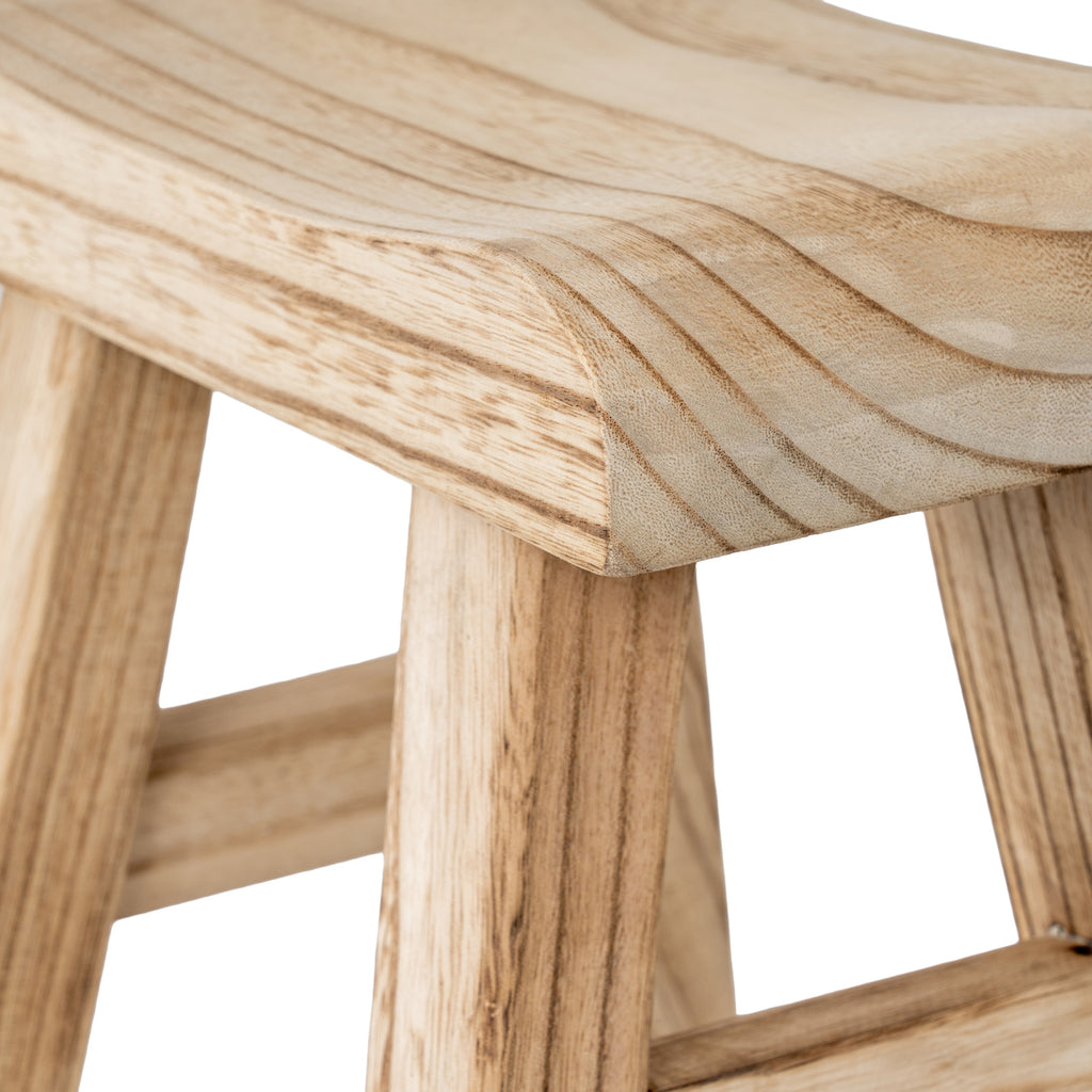Close-up of the stool's curved seat corner with pale tan colouring, fine grain texture and darker lines above the splayed legs.