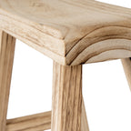 Close-up of the stool seat corner showing curved dark grain markings, the shallow dip in the top and streaked legs below.