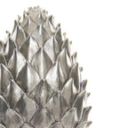 Close-up of the pinecone finial's pointed silver-coloured scales, showing fine surface markings and dark lines between the overlapping layers.