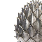 Close-up of the pinecone finial's overlapping scales, showing bright silver-coloured ridges, darker recesses and mottled surface markings.