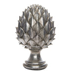 Silver-coloured pinecone finial with layered pointed scales, a narrow pedestal neck and rounded stepped base against white.