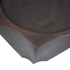 Close-up of the lightly brushed bronze top, inset circular edge and pointed corner above two curved sides.