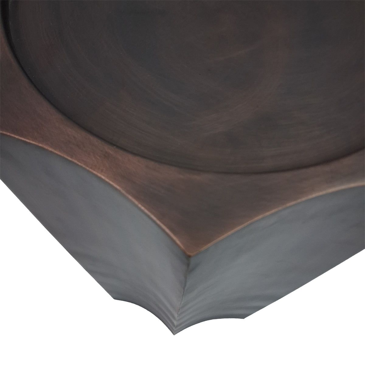 Close-up of the lightly brushed bronze top, inset circular edge and pointed corner above two curved sides.