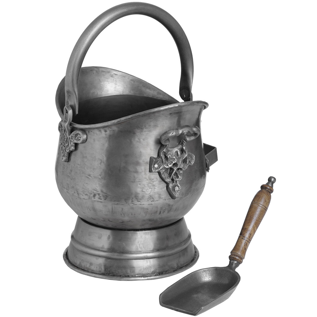 Reverse view of the coal bucket showing decorative scroll-like fittings, with the wooden-handled shovel placed to the right.