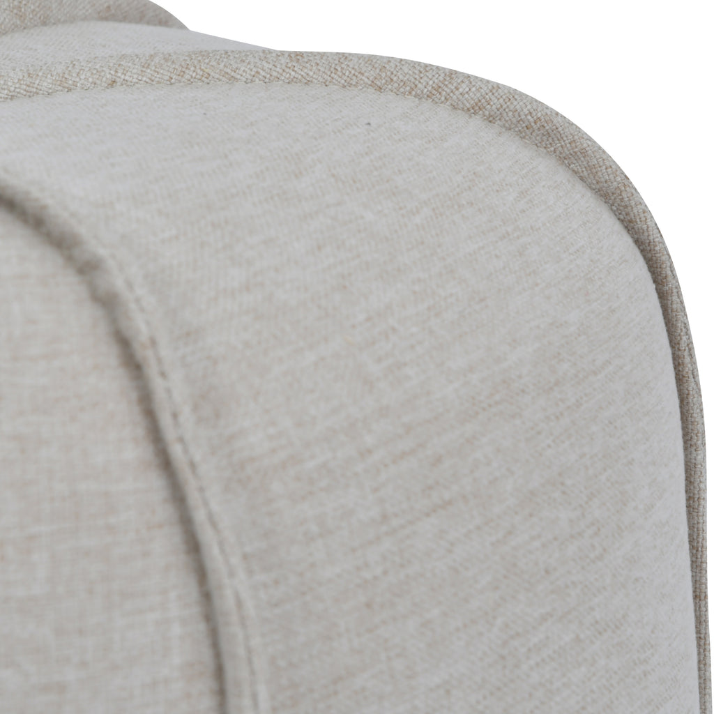Close-up of matching piping over the rounded shoulder of the footstool, showing the oatmeal linen weave.