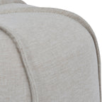 Close-up of matching piping over the rounded shoulder of the footstool, showing the oatmeal linen weave.