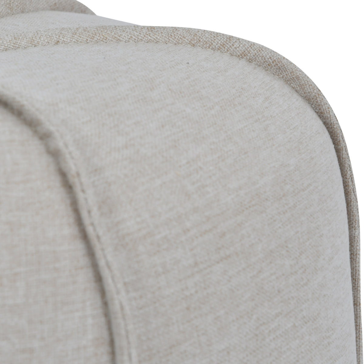 Close-up of matching piping over the rounded shoulder of the footstool, showing the oatmeal linen weave.