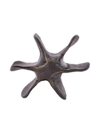 End view of the seed pod sculpture, showing six curved projections around a bronze-toned central area.