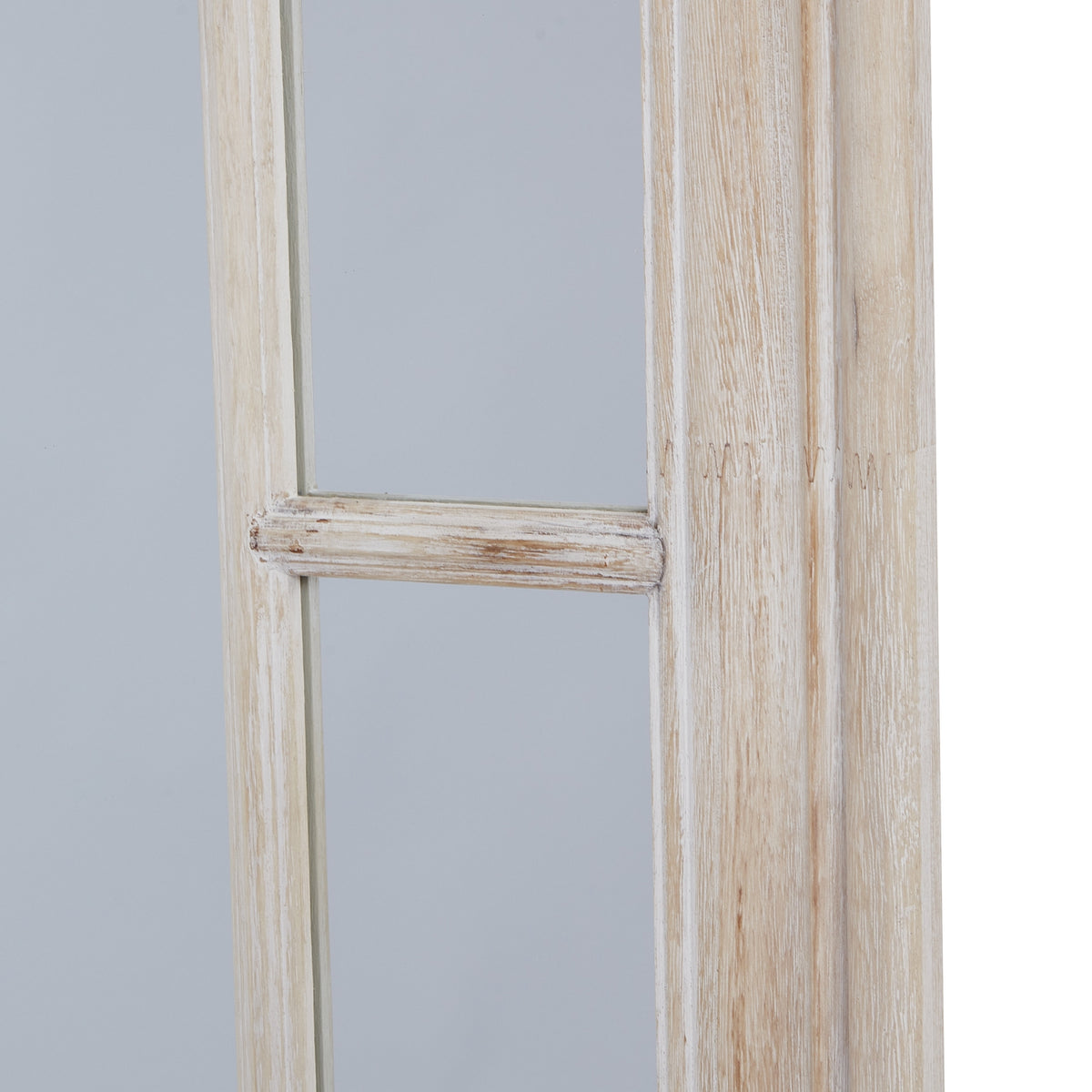 Close-up of a horizontal divider in the mirror's side border, beside the pale frame with warm beige streaks.