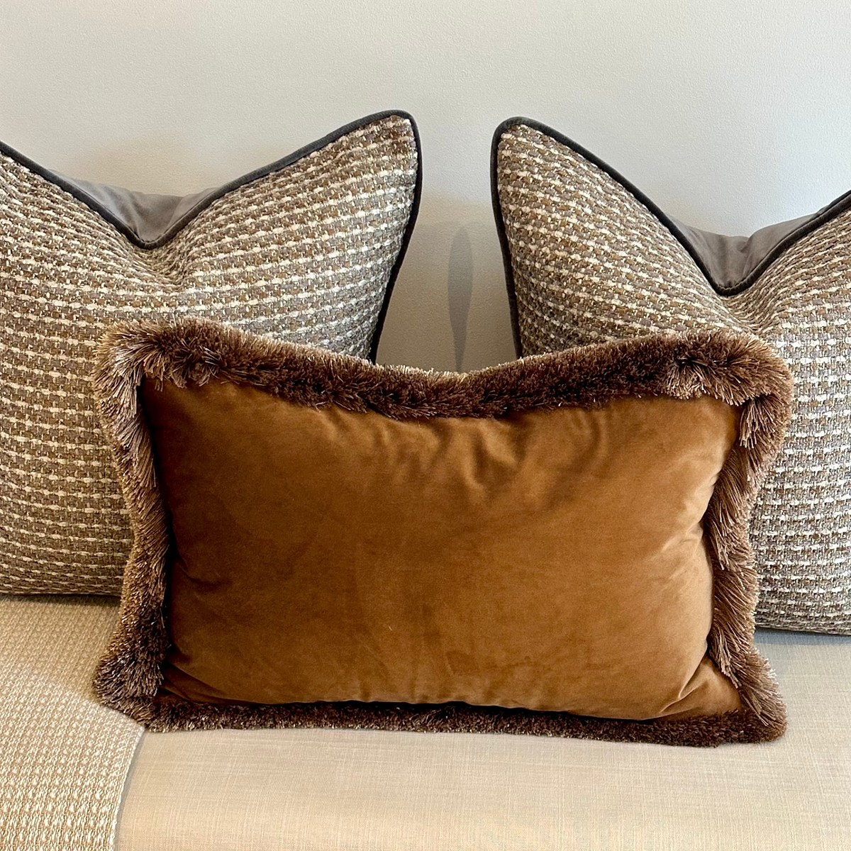 Serena Lumbar Cushion with brown fringe styled in front of neutral cushions