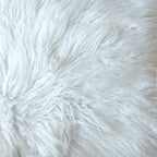 Close-up of the pouffe's ivory shaggy surface, with long strands lying in different directions.