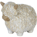Three-quarter front view of a rounded white Highland cow ornament with beige horns and muzzle, a shaggy textured coat and short feet.