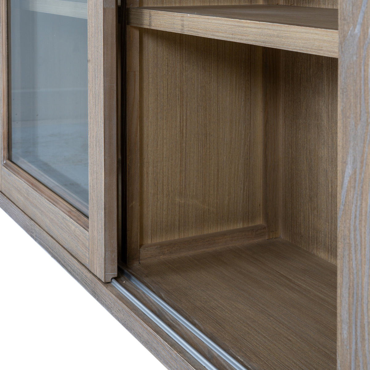 Close-up of the lower cabinet interior, showing the grain of the back and side panels beside the glazed frame and bottom track.