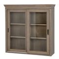 Angled view of the grey-brown upper cabinet with a shaped crown, glazed front and recessed pulls.